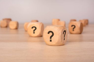 Tahta yüzeyinde siyah soru işaretleri olan tahta zarlar belirsizlik, seçim ve merakı temsil ediyor. Sorun çözme, karar verme ve gizem gibi kavramlar için ideal.