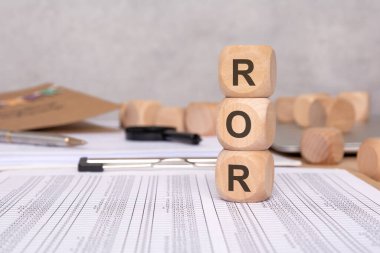 Finansal tablolarda 'ROR' harfleri olan üç tahta küp. Gelir Dönüşü (ROR), finansal performans ve iş karlılık analizi kavramı. Finansal ve iş konuları için ideal