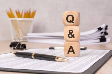 Ahşap küpleri bir masanın üzerinde dokümanlar, kalem ve ofis malzemeleriyle bir araya toplanmış, iş görüşmelerini, problem çözmeyi, profesyonel ortamlarda eğitim ve iletişimi temsil eden tahtalar..