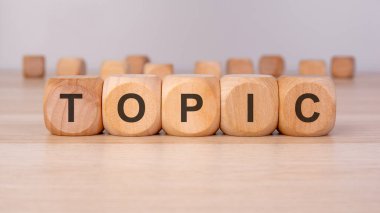 TOPIC metni kahverengi arkaplandaki tahtadan küplere yazılır