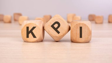 Tahta bir masanın üzerinde KPI bulunan tahtadan küpler, anahtar performans göstergeleri, başarı ölçümü, iş stratejisi, analitik, verimlilik, şirket hedefleri, üretkenlik, değerlendirme ve veri odaklı karar verme mekanizmasını temsil ediyor