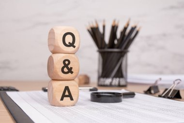 Finans belgesinde soru-cevap harfleri olan üç tahta blok var. Ofis malzemeleri arka planda. bilgi, iletişim, iş ve karar verme kavramı