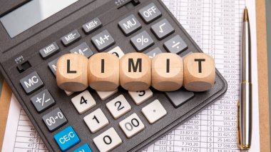 LIMIT kelimesi, finansal tablolar ve kalemle çevrili bir hesap makinesine yerleştirilmiş ahşap bloklardan oluşmuştur. Finansal sınırlar, bütçe kısıtlamaları ve iş kısıtlamaları kavramı.