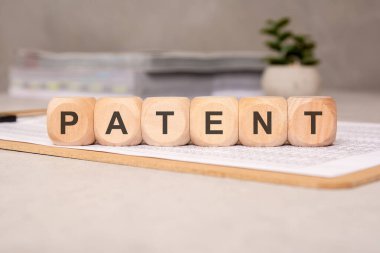 İnovasyon, hukuki haklar ve fikri mülkiyet korumasını temsil eden bir belge kağıdının üzerinde duran ahşap bloklarla hecelenmiş PATENT.
