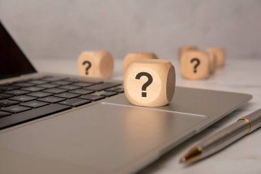 Laptop klavyesinde soru işareti olan tahta blok, yardımı, SQ 'yu veya dijital veya iş bağlamında sığ bir alan derinliğine sahip bir soruşturmayı sembolize ediyor