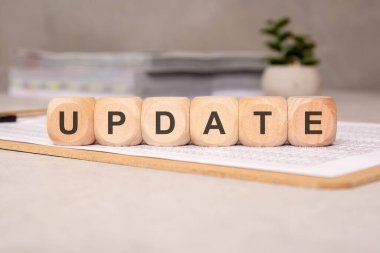 UPDATE sözcüğünü heceleyen altı tahta küp, mali belgelerle birlikte bir panoya yerleştirilmiş,