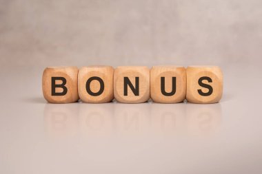 BONUS hafif bir yüzeyde tahta küplerle hecelenir. Yansıtılmış harfler simetri ekler. HR, motivasyon, ödül ve iş teşvikleri için ideal.