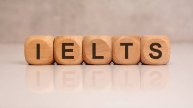 Yansıtıcı yüzeydeki ahşap bloklar kullanılarak gösterilen IELTS kısaltması. Uluslararası dil testi kavramı.