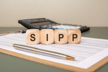 Tahta bloklar SIPP Kişisel Yatırımlı Emeklilik Emeklilik Finansal Evraklarına Emeklilik Planlama Konseptinde bir kalem ve hesap makinesiyle yerleştirildi.