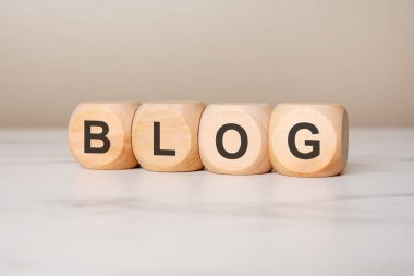 BLOG sözcüğüyle tahta blokların kapatılması, blog oluşturma, içerik oluşturma, dijital medya, çevrimiçi iletişim, sosyal medya pazarlaması, kişisel web sitesi ve yaratıcı yazı kavramını temsil ediyor.