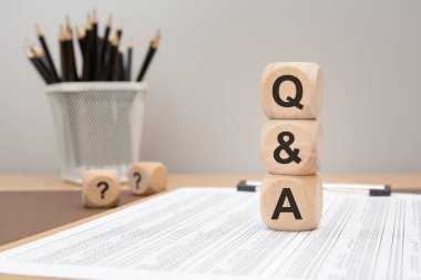 Finans tablosunda soru-cevap harflerini gösteren tahta küpler. kurumsal iletişimde veya ofis ortamında müşteri desteğinde soru ve cevap konsepti.