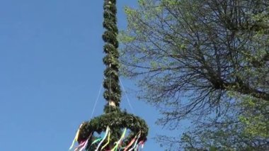 Mavi gökyüzü ve rüzgarla süslenmiş renkli kurdelelerle mayo direği