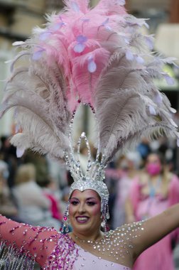 20 Şubat 2022 - Torrevieja, İspanya. Gösterişli pembe karnaval kostümlü, mücevherli ve tüylü güzel bir kadın İspanya 'daki yıllık karnavalda sokakta dans ediyor. Turizm ve eğlence.