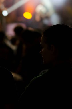 12 Ekim 2022 - Berlin, Almanya. Kadın silueti sahne ışıklarının bulanık arka planına karşı yan yana bakar. Rahatlama ve müzik zevki kavramı.