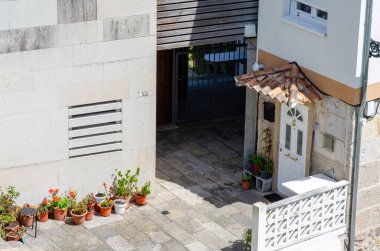 Seramik çatılı, beyaz kapılı ve canlı saksı bitkileriyle büyüleyici bir yerleşim yeri girişi aydınlık bir günde kentsel atmosfer yaratıyor..