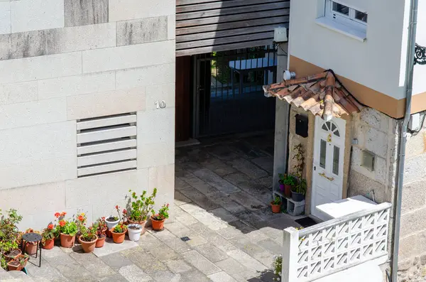 Seramik çatılı, beyaz kapılı ve canlı saksı bitkileriyle büyüleyici bir yerleşim yeri girişi aydınlık bir günde kentsel atmosfer yaratıyor..