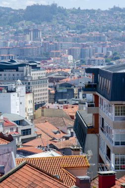 Yoğun nüfuslu bir şehir manzarası geleneksel kırmızı kiremitli çatıları ve güneşli bir günde çekilen çağdaş apartman binaları..