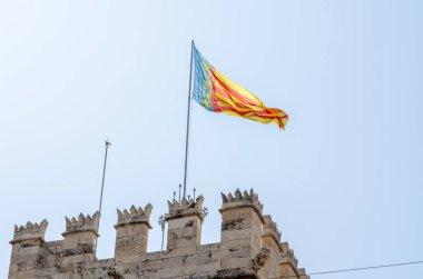 Geleneksel Valencia bayrağı gururla Valensiya 'nın göbeğindeki bir ortaçağ taş kalesinin tepesinde dalgalanıyor. Bölgesel mirası ve İspanyol tarihini sembolize ediyor..