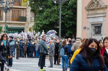 Bir şehir caddesinde ellerinde pankartlar ve renkli şemsiyelerle protesto yapan büyük bir grup insan. Farklı yetişkinlerin açık havada halk eylemlerini gösterdikleri şehir gösteri sahnesi.