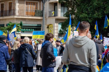 İnsanlar Ukrayna meydanında toplanıp Ukrayna 'yı destekleyen barışçıl bir protesto gösterisinde Ukrayna bayrakları sallıyor ve savaş karşıtı pankartlar tutuyor, çatışmalara karşı birlik ve aktivizm gösteriyorlar..