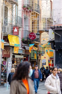 Valencia, İspanya 'nın eski bir kasabasında renkli Valencia bayrakları, güneşli bir günde yerli ve turistler dükkanları ve kafeleri keşfederken canlı bir caddeyi süslüyor..