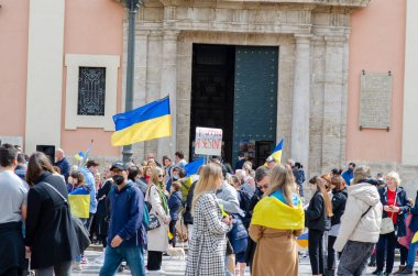 Tarihi bir binanın önünde Ukrayna bayrakları ve bayraklar taşıyan insanların, Avrupa kentindeki bir kentte dayanışma ve protesto gösterileri.