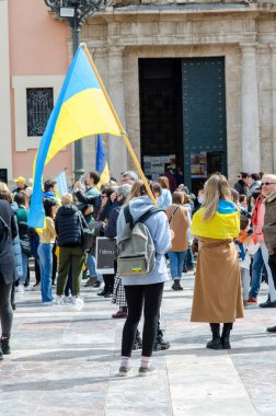Bir grup insan, Ukrayna 'yı desteklemek için barışçıl bir protesto için şehir meydanında toplanıp Ukrayna bayrakları taşıyor..