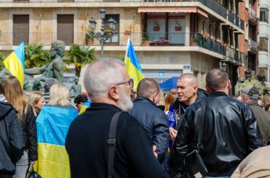 Bir grup insan, Ukrayna 'ya destek ve dayanışma göstermek amacıyla barışçıl bir miting sırasında bir Avrupa şehir meydanında Ukrayna bayrakları taşıyor..