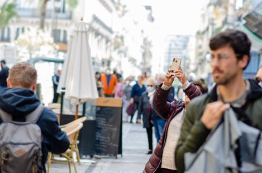 Yürüyen, gezen, gezen ve akıllı telefonlardan anılarını yakalayan insanların olduğu hareketli bir şehir manzarası. Avrupa 'nın pitoresk bir bölgesinde şehir turizmi ve modern yaşam tarzı.