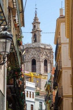 Valencia, İspanya 'nın göbeğindeki renkli konut binalarının üzerinde yükselen Gotik çan kulesinin resimli görüntüsü. Kentsel mimari ve seyahat kavramı.