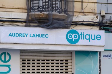 Kalabalık bir caddede modern markalaşma ile kapalı bir optik mağaza, şık balkon ve mimari detaylara sahip. Perakende ve kentsel temalar için uygun.