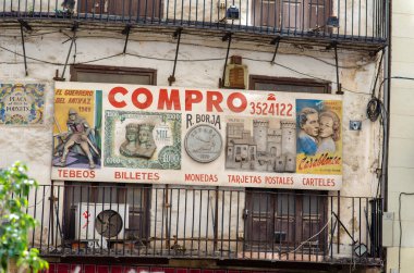 Valencia, İspanya 'da kırsal bir binanın ön cephesinde hakiki eski reklam tabelası. Çizgi roman, bozuk para ve koleksiyon eşyaları almayı teklif ediyor. Yerel kültür ve sokak atmosferi.