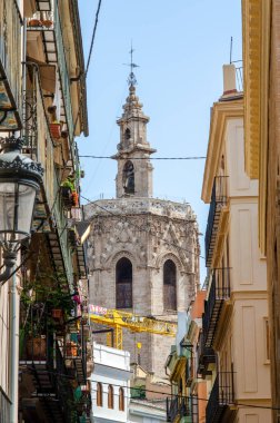 Güneşli bir günde ikonik katedral çan kulesinin yer aldığı tarihi mimarisi ve bereketli balkonlarıyla Valencia 'nın büyüleyici sokak manzarası. Seyahat ve kültür temaları için mükemmel.