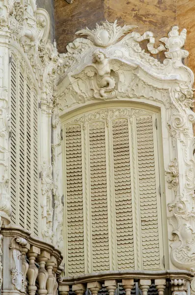 Zarif barok penceresi, karmaşık pervazlarla çevrili ve klasik Avrupa cephesinde bir melek figürü, mimari arka plan için ideal..