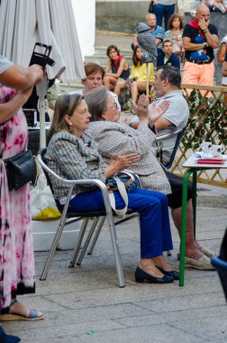 Avrupa 'daki bir kasaba meydanında yaşlı kadınlar toplanıp alkışlıyorlar. Toplum etkinliğinden zevk alan bir grup yetişkin, canlı ve dostane bir ortam yaratıyor..