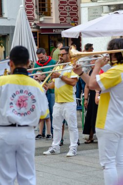 Sarı ve beyaz üniformalı müzisyenler canlı bir şehir sokak festivali sırasında neşeli bir kalabalığa canlı bir müzik icra ederek enerjik ve şenlikli bir atmosfer yarattılar..