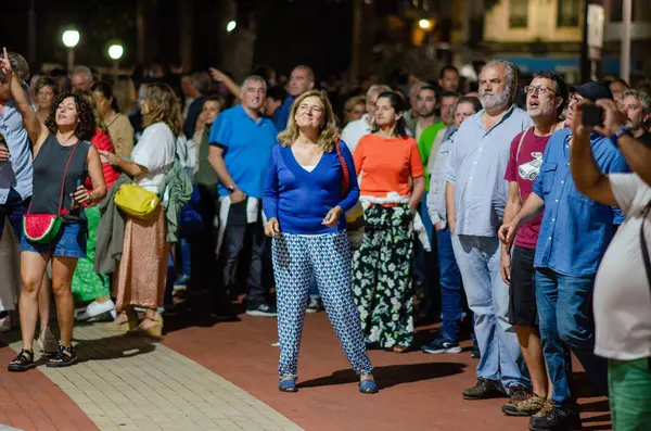 Büyük bir grup yetişkin, kentteki bir açık hava etkinliğinde toplanarak, canlı bir festival veya konser sırasında olumlu duygular dile getirdiler ve birbirleriyle etkileşime geçtiler..
