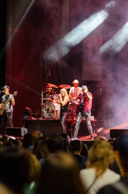 Canlı sahne ışıkları ve atmosferin keyfini çıkaran tezahüratlı bir kalabalıkla bir gece konserinde canlı performans sergileyen enerji bandosu. Müzisyenler, şarkı söylemek ve eğlenmek.