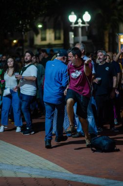 Canlı bir grup insan gece şehir parkında toplanıyor, açık hava festivalinde dans ediyor ve sosyalleşiyorlar, otantik şehir gece hayatı anlarını yakalıyorlar..