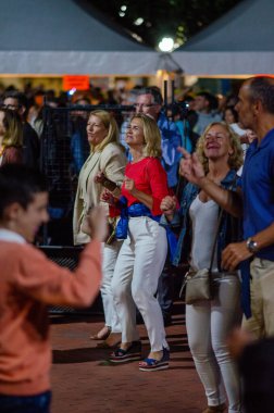 Neşeli bir grup yetişkin açık hava etkinliğinde dans ediyor, neşeli atmosferi ve parlak ışıkları var. Canlı müzik festivali, mutlu insanlar, sosyal toplantı..