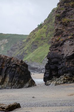 Dramatik sahil uçurumları ve yemyeşil tepeler uzak kumlu bir sahil boyunca sakin bir sahne oluşturur, doğa, macera veya seyahat kavramları için mükemmeldir..