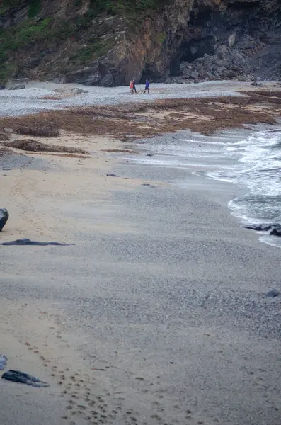Okyanus dalgaları ve dramatik kayalık uçurumların kıyısında yürüyen iki kişi. Yolculuk ve macera temaları için mükemmel..