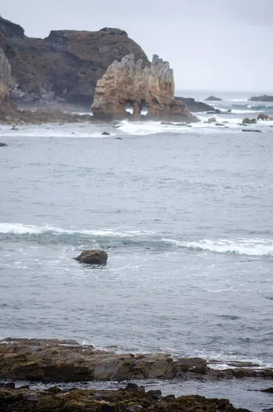 İspanya 'nın Asturias kentindeki kasvetli ve bulutlu bir günde dalgaların çarptığı dramatik bir sahil kayalığı. Manzaralı deniz manzarası ve doğa temaları için ideal bir yer..