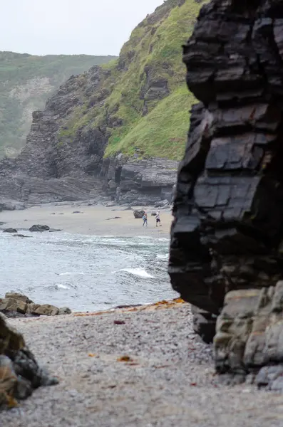 Dramatik uçurumlar ve kayalık kıyı şeritleriyle çevrili uzak bir sahil boyunca yürüyen iki kişi, seyahat ve doğa temaları için huzurlu ve maceralı bir kıyı manzarası yaratıyor..