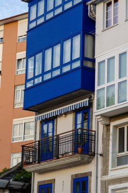 Modaya uygun mavi balkon ve eşleşen kapılar, şehir mimarisinde çağdaş bir tasarım sunan modern bir apartman binasının ön cephesini vurguluyor..