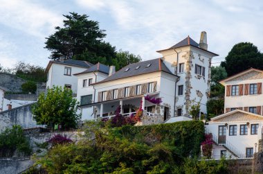 Tepenin yamacındaki büyüleyici Akdeniz villası, yeşillik ve çiçek açan çiçeklerle çevrili, seyahat ve emlak kavramları için mükemmel. Akşam güneşi sakin atmosferi güçlendirir..