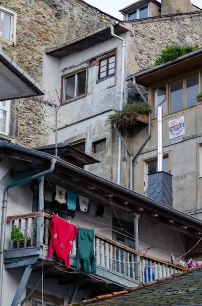 Yıpranmış bir konut binasında asılı giysileri, dokulu taş duvarları ve şehir ve seyahat temaları için ideal otantik Avrupa atmosferi olan büyüleyici ahşap bir balkon bulunuyor..