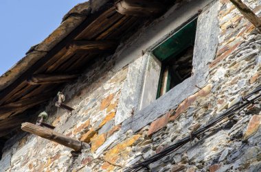 Eski taş işçiliği, geleneksel ahşap pencere ve güneş ışığıyla aydınlatılan klasik çatı kirişleri ile tarihi kırsal yapı cephesi. Mimarlık ve miras temaları için mükemmel.