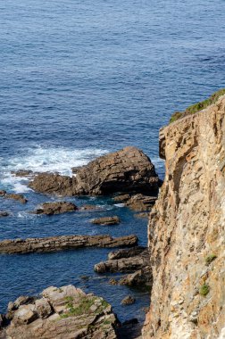 Dramatik kayalık kayalık tarafı canlı mavi denizle buluşur, sakin bir kıyı manzarası yaratır doğa, seyahat ve manzara tasarımları için mükemmeldir..