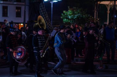 İspanya 'da canlı bir Cadılar Bayramı karnavalı sırasında renkli bir sokak grubu neşeli bir kalabalık eğlendiriyor. Kostümlü müzisyenler, gece lambaları, neşeli atmosfer.